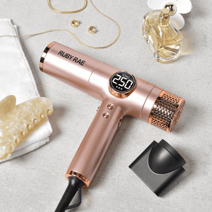 Rose gold hair dryer with digital display on a light gray surface, surrounded by beauty products.