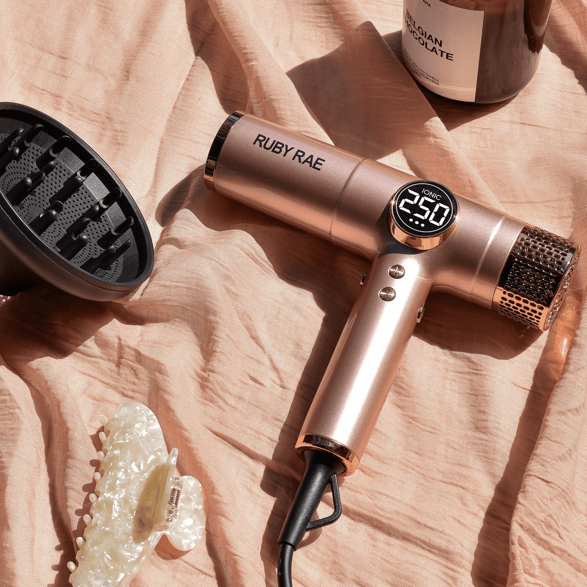 Rose gold hair dryer with 'Ruby Rae' branding on a textured surface.